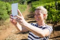 Happy woman talking selfie with mobile phone in vineyard