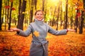 Happy woman throwing leaves around on an autumns day. Autumn leaves falling on happy young woman in colourful forest park. Royalty Free Stock Photo