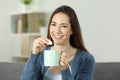 Happy woman throwing sugar into mug looking at you Royalty Free Stock Photo