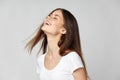 Happy woman tilted her head back and laughs on a light background with closed eyes