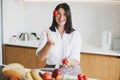 Happy woman tossing up cherry tomato and smiling in modern  kitchen. Having fun and making salad Royalty Free Stock Photo