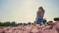 Happy woman touching flowers at walk with camera in tulip field in sunny day.