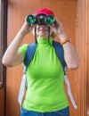 Happy woman tourist with backpack looking through binoculars, search purpose, gathering information, outdoor activity Royalty Free Stock Photo