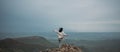 Happy woman tourist hiking up mountain enjoying nature. Landscape in cloudy gloomy windy weather. Female in white shirt