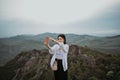 Happy woman tourist hiking up mountain enjoying nature. Landscape in cloudy gloomy windy weather. Smiling female in