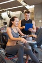 Happy woman with trainer on exercise bike in gym Royalty Free Stock Photo