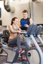 Happy woman with trainer on exercise bike in gym Royalty Free Stock Photo