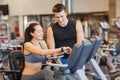 Happy woman with trainer on exercise bike in gym Royalty Free Stock Photo