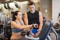 Happy woman with trainer on exercise bike in gym Royalty Free Stock Photo