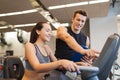 Happy woman with trainer on exercise bike in gym Royalty Free Stock Photo