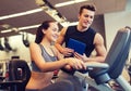 Happy woman with trainer on exercise bike in gym Royalty Free Stock Photo