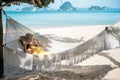 Happy Woman Traveler is relaxing in a hammock on the paradise beach. Female tourist in yellow dress rest near tropical sea. Royalty Free Stock Photo