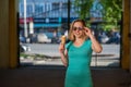 A happy woman in a turquoise dress stands in the yard and eats a waffle cone on a warm summer day. Beautiful blonde in sunglasses Royalty Free Stock Photo