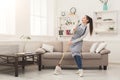 Woman in uniform cleaning home with mop and having fun