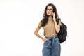 Happy woman university student with backpack and books talking on cell phone, looking out of frame on white background Royalty Free Stock Photo