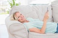 Happy woman using digital tablet while lying on sofa Royalty Free Stock Photo