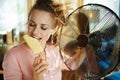 Happy woman using electric metallic fan while eating ice cream Royalty Free Stock Photo