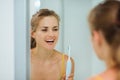 Happy woman using electric toothbrush in bathroom