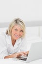 Happy woman using her laptop on her bed looking at camera Royalty Free Stock Photo