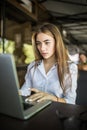 Happy woman using laptop at cafe. Young beautiful girl sitting in a coffee shop and working on computer Royalty Free Stock Photo