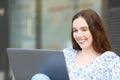 Happy woman using laptop seated in the street Royalty Free Stock Photo