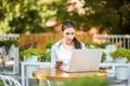 Happy woman using laptop and smartphone in cafe. Young beautiful girl sitting in a coffee shop and working on computer Royalty Free Stock Photo