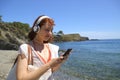 Happy woman using phone listening to music on the beach Royalty Free Stock Photo