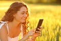 Happy woman using phone in a wheat field at sunset Royalty Free Stock Photo