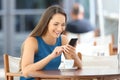 Happy woman using a smart phone in a bar terrace Royalty Free Stock Photo