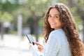 Happy woman using smart phone looking at you outside Royalty Free Stock Photo