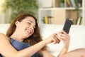 Happy woman using phone lying on a couch at home Royalty Free Stock Photo