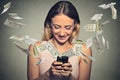 Happy woman using smartphone with dollar bills flying away from screen Royalty Free Stock Photo