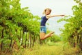 Happy woman in a vineyard is jumping and having fun during the h