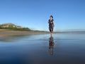 A happy woman walking alone on the beach on a  bright and clean blue sky background. Person with smiling face walking on bare feet Royalty Free Stock Photo