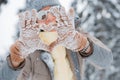 woman mittens dressed fashionable gray stands with her back makes heart gesture with her hands against background snowy