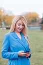 Happy woman walking and using a smart phone on the street in autumn