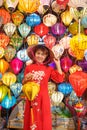 Happy woman wearing Ao Dai Vietnamese dress with colorful lanterns, traveler sightseeing at Hoi An ancient town in central Vietnam Royalty Free Stock Photo