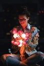 Happy woman wearing glowing jacket with sequins is holding light balls in her hands