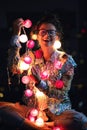 Happy woman wearing glowing jacket with sequins is holding light balls in her hands