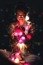 Happy woman wearing glowing jacket with sequins is holding light balls in her hands