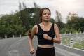 Happy woman wearing sportswear jogging in the park. Young beautiful asian female in sports bra running outdoor. Workout Royalty Free Stock Photo