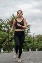 Happy woman wearing sportswear jogging in the park. Young beautiful asian female in sports bra running outdoor. Workout Royalty Free Stock Photo