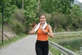 Happy woman wearing sportswear jogging in the park. Young beautiful asian female in sports bra running outdoor. Workout Royalty Free Stock Photo