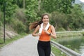Happy woman wearing sportswear jogging in the park. Young beautiful asian female in sports bra running outdoor. Workout Royalty Free Stock Photo