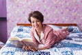 Happy woman wears pajama and relaxing at home and reading a book. Stay home. Quarantine pandemic coronavirus concept. Royalty Free Stock Photo