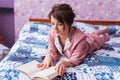 Happy woman wears pajama and relaxing at home and reading a book. Stay home. Quarantine pandemic coronavirus concept. Royalty Free Stock Photo