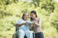 Happy Woman in a wheelchair reading a book with her daughter Royalty Free Stock Photo