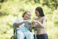 Happy Woman in a wheelchair reading a book with her daughter Royalty Free Stock Photo