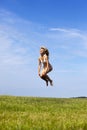 The happy woman in white bikini jumps in a summer green field against the blue sky Royalty Free Stock Photo