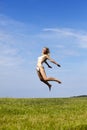 The happy woman in white bikini jumps in a summer green field against the blue sky Royalty Free Stock Photo